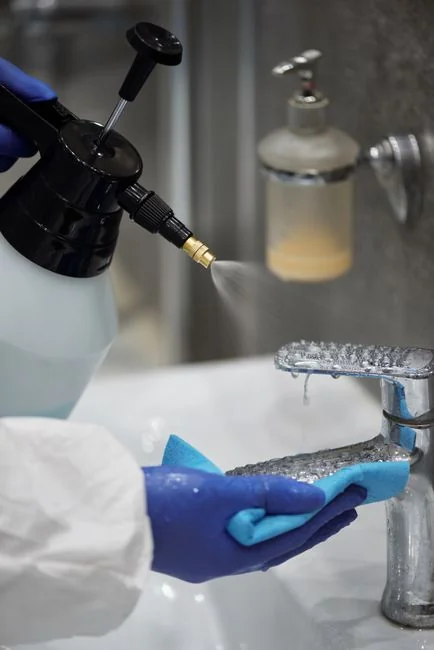 Close-up of hand cleaning window with squeegee outdoors using yellow gloves.